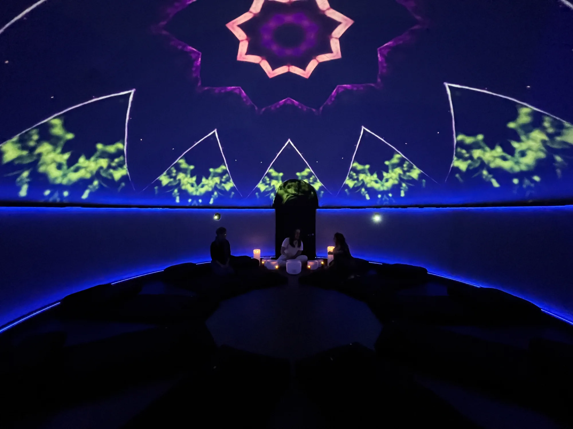 Three participants seated in the Sensorium dome under a mandala projection - the dome experience in session